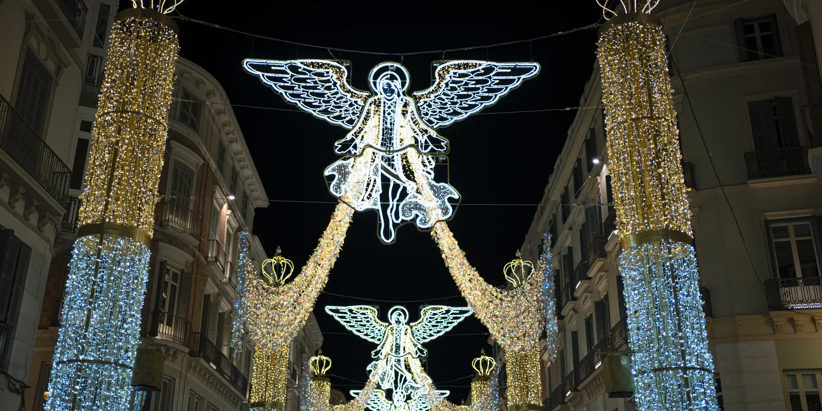 Christmas light arches with illuminated angels over a street in central Málaga at night
