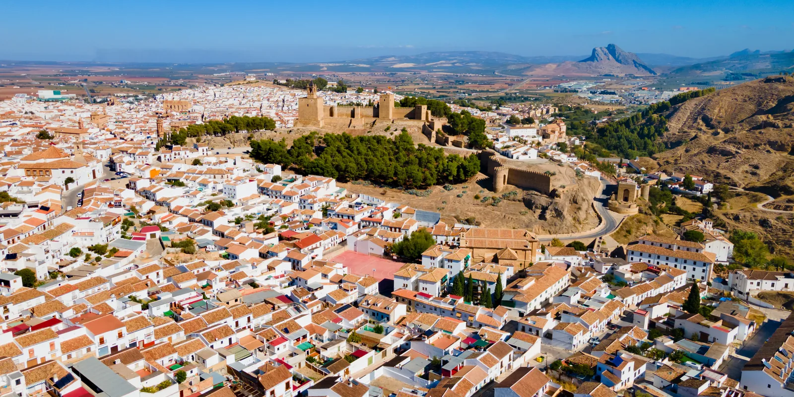 Aerial view of Antequera's white houses, with the Alcazaba on the hill and the plain and mountains beyond