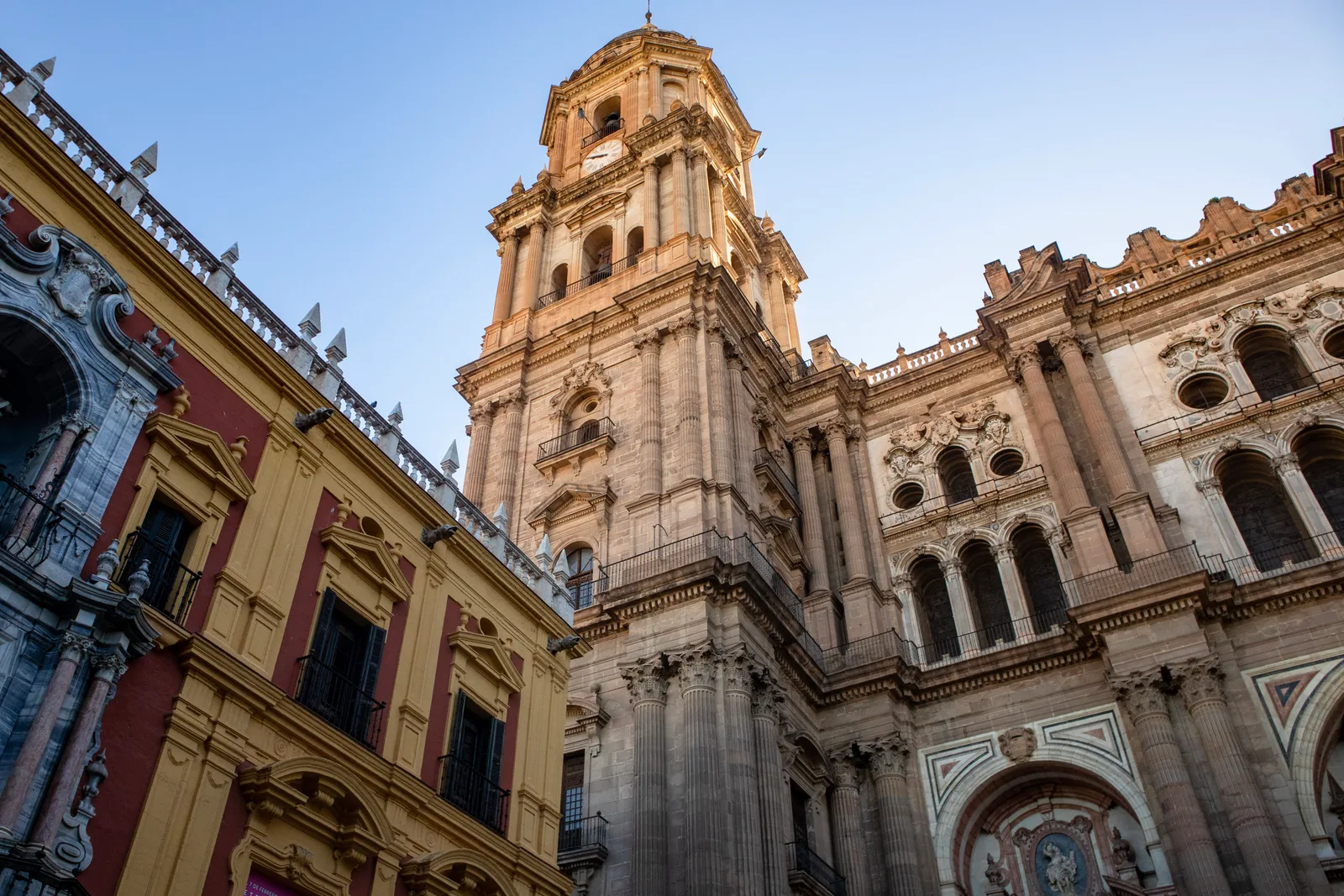 Torre y fachada barroca de la catedral vistas desde abajo, con el Palacio Episcopal de fachada roja y ocre a la izquierda