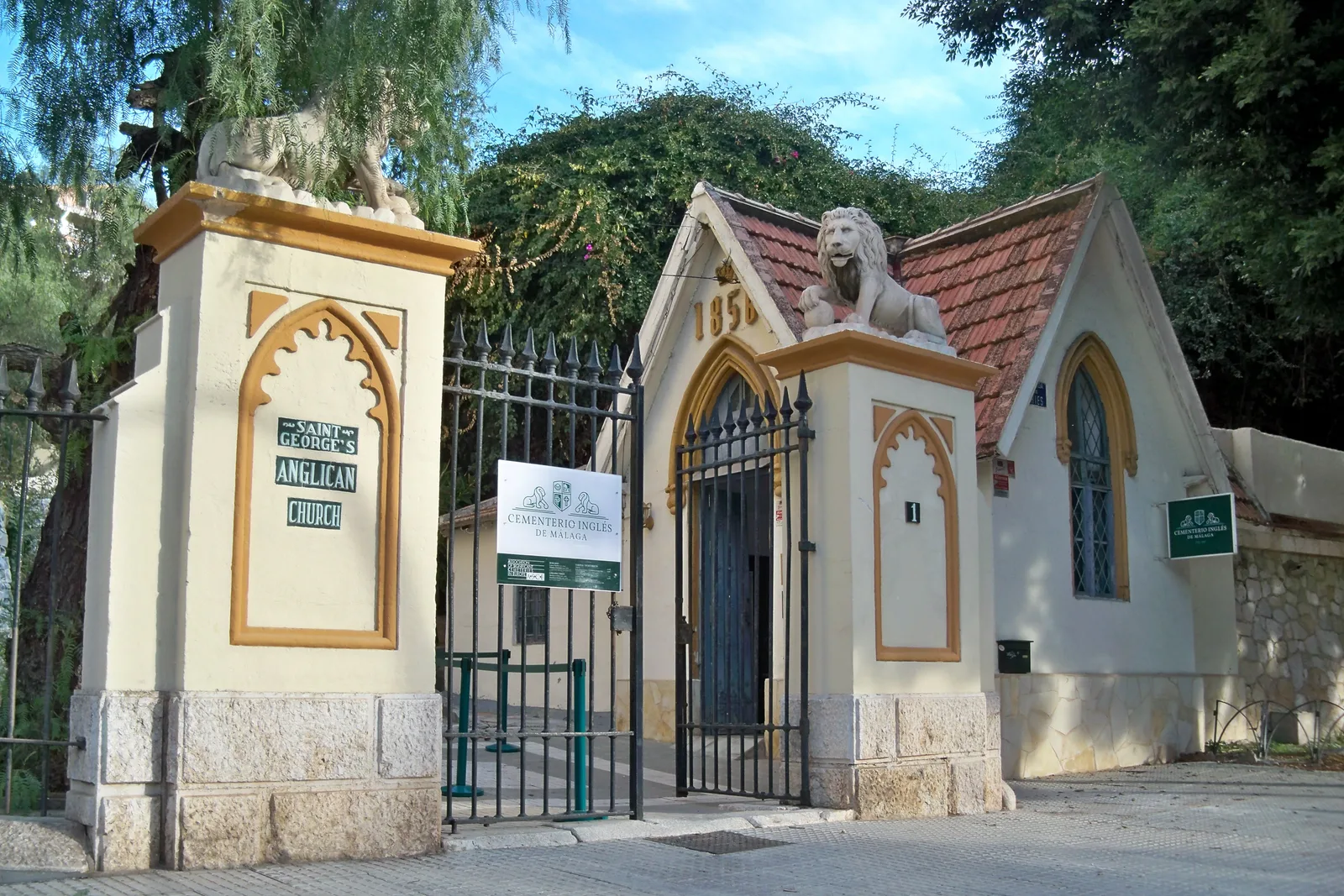 Portada de entrada con dos pilares coronados por leones de piedra y la caseta de estilo neogótico